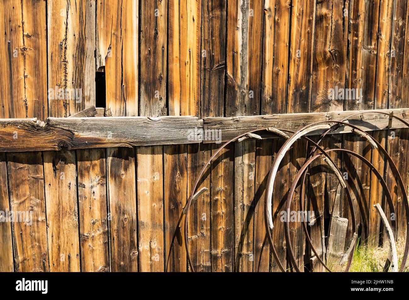 Background of old rusted wagon wheels against a weathered wood barn wall Stock Photo