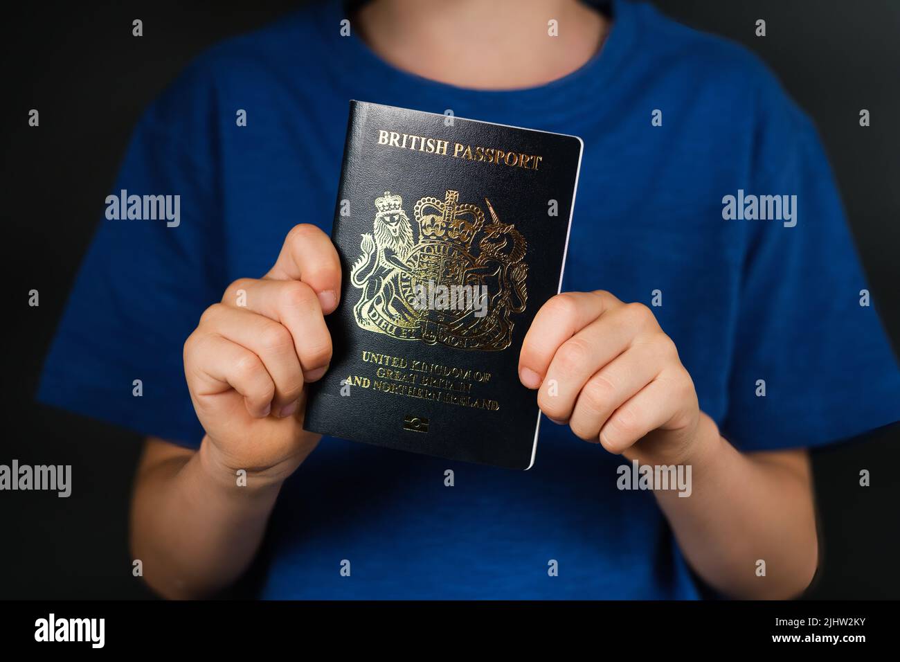 British biometric passport seen in hands of a child. Passport of United Kingdom of Great Britain and Northen Ireland. Concept for travel and immigrati Stock Photo