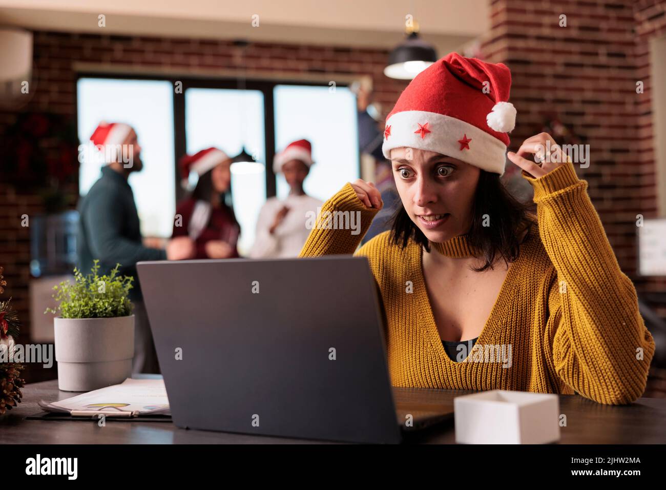 Irritated unhappy employee working in noisy office, feeling disturbed by colleagues in workplace decorated with festive holiday ornaments. Tired overworker person in corporate space. Stock Photo