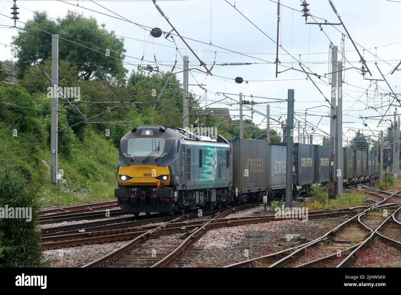 DRS class 88 electro-diesel number 88005, Minerva, on West Coast Main Line approaching Carnforth with northbound container train on  29th June 2022. Stock Photo