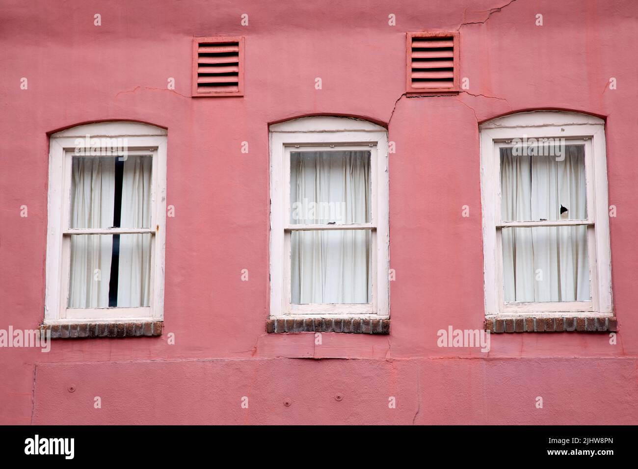 Pink building facade with white framed windows, background. Stock Photo