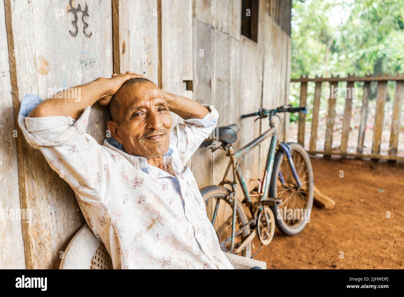 Latin grandfather with arms above his head relaxing in his poor house Stock Photo Alamy