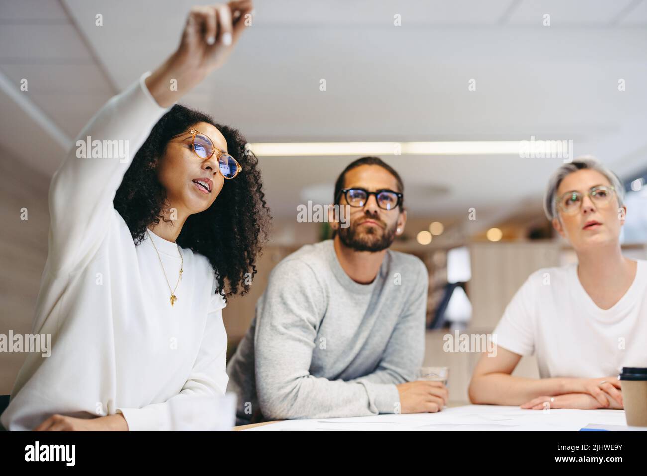 Smart businesswoman sharing her ideas with her team during a meeting. Group of creative design professionals having a discussion while working on a ne Stock Photo