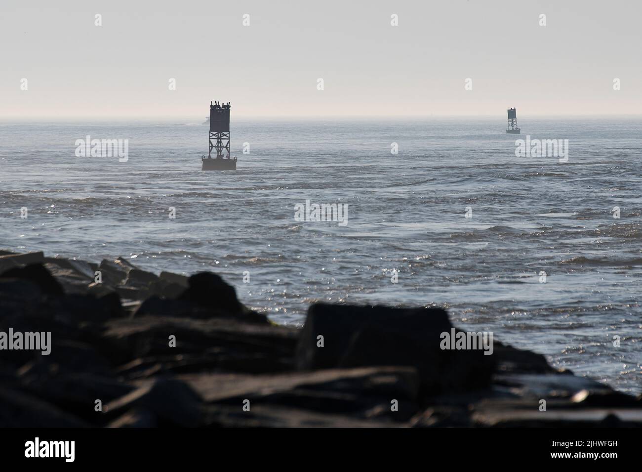A set of channel buoys mark an inlet on a sunny, misty morning along the Atlantic coastline. Stock Photo