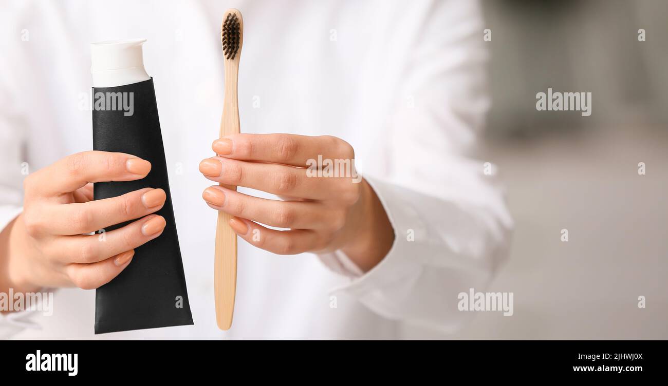 Woman with tube of activated charcoal tooth paste and bamboo brush, closeup Stock Photo