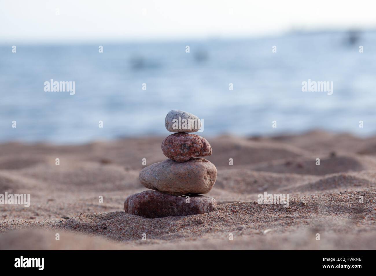 Round stones lie on top of each other in a column on the seashore on a ...