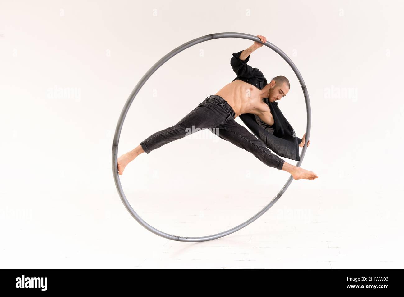 Circus acrobat doing a one leg trick on a spinning cyr wheel isolated on a white background with advertising copyspace Stock Photo