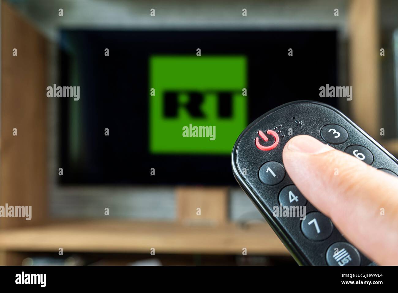 Barnaul. Russia June 20, 2022: remote control in hand and the logo of the Russian news channel rt on the TV screen Stock Photo