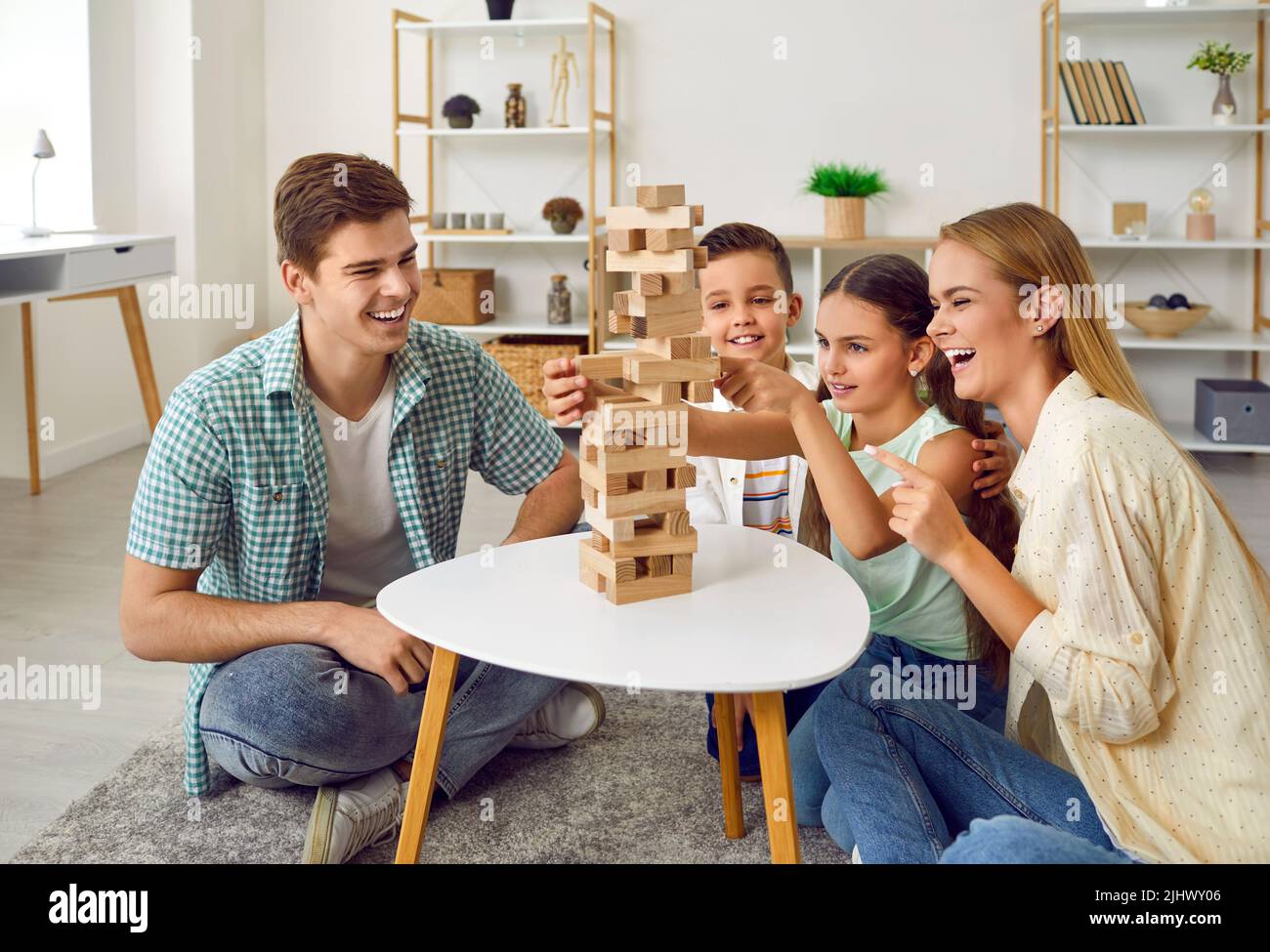 Happy parents and little children playing board games and having fun together at home Stock Photo