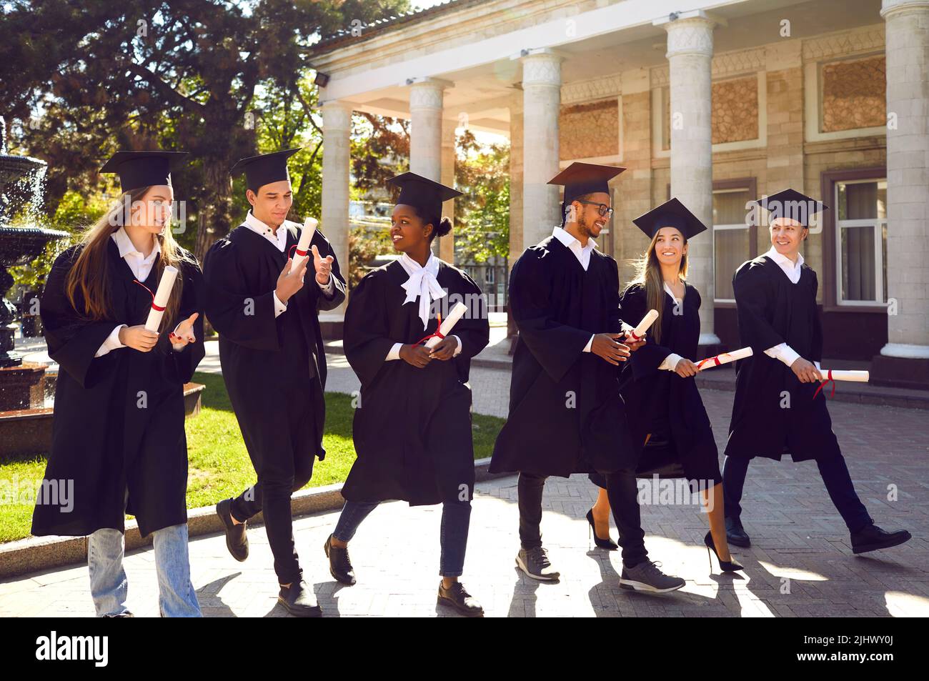 Group of happy multiracial graduates in campus yard after outdoor graduation ceremony Stock Photo