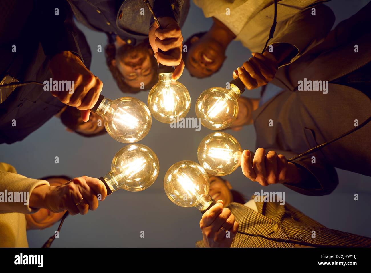 Happy diverse business team holding light bulbs as symbol of sharing creative ideas Stock Photo