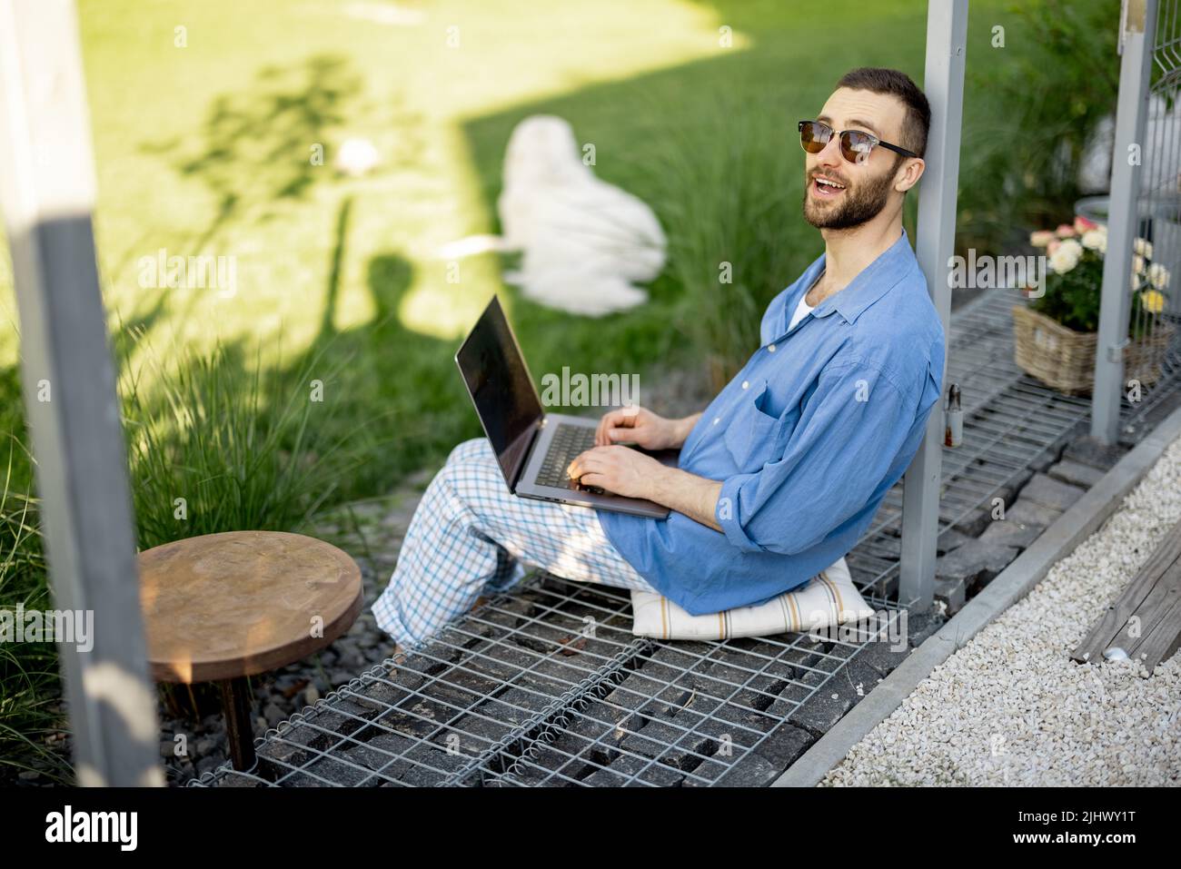 Man works on laptop while sitting at backyard Stock Photo