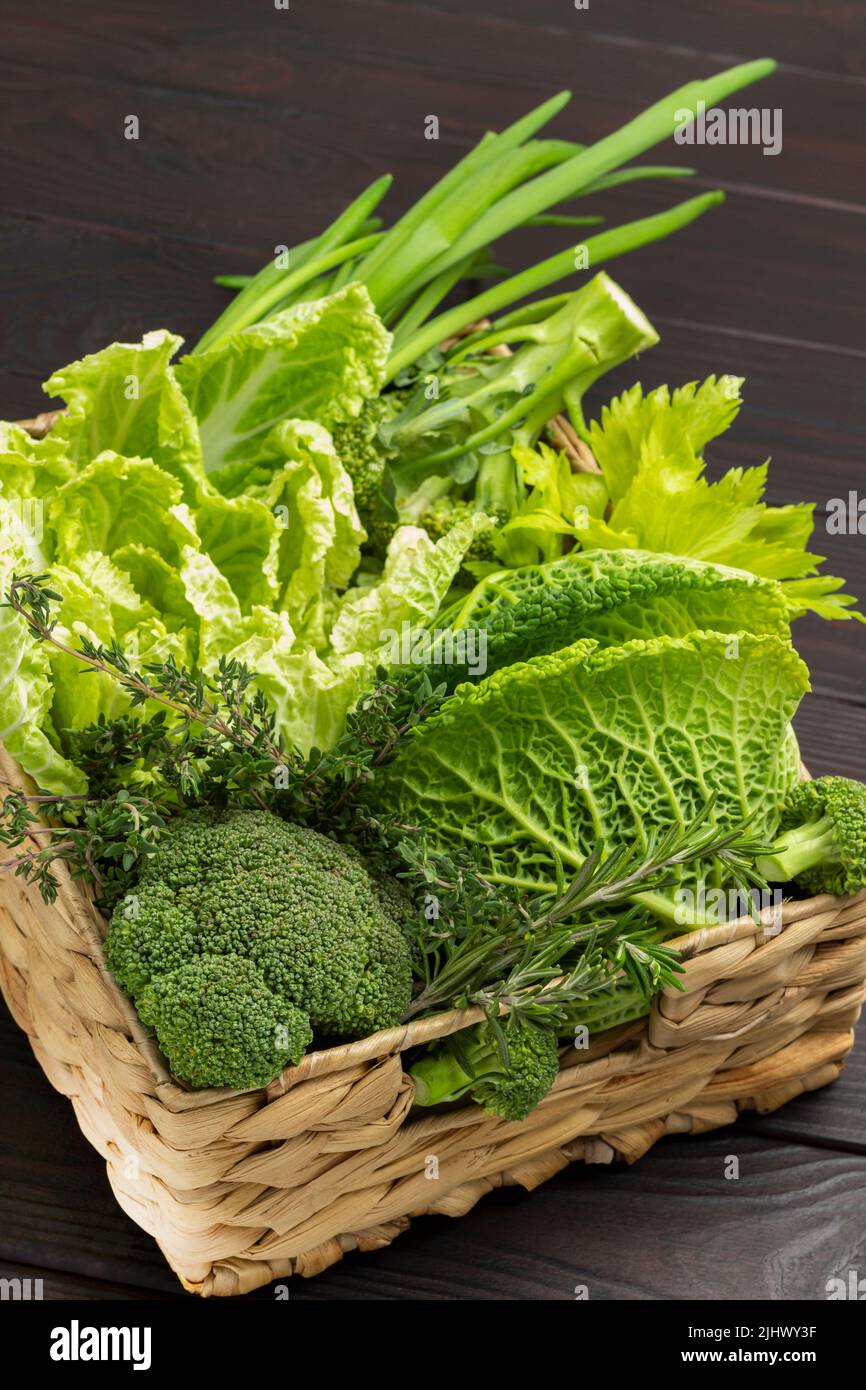 Set of green fresh vegetables and herbs in wicker basket. Top view ...