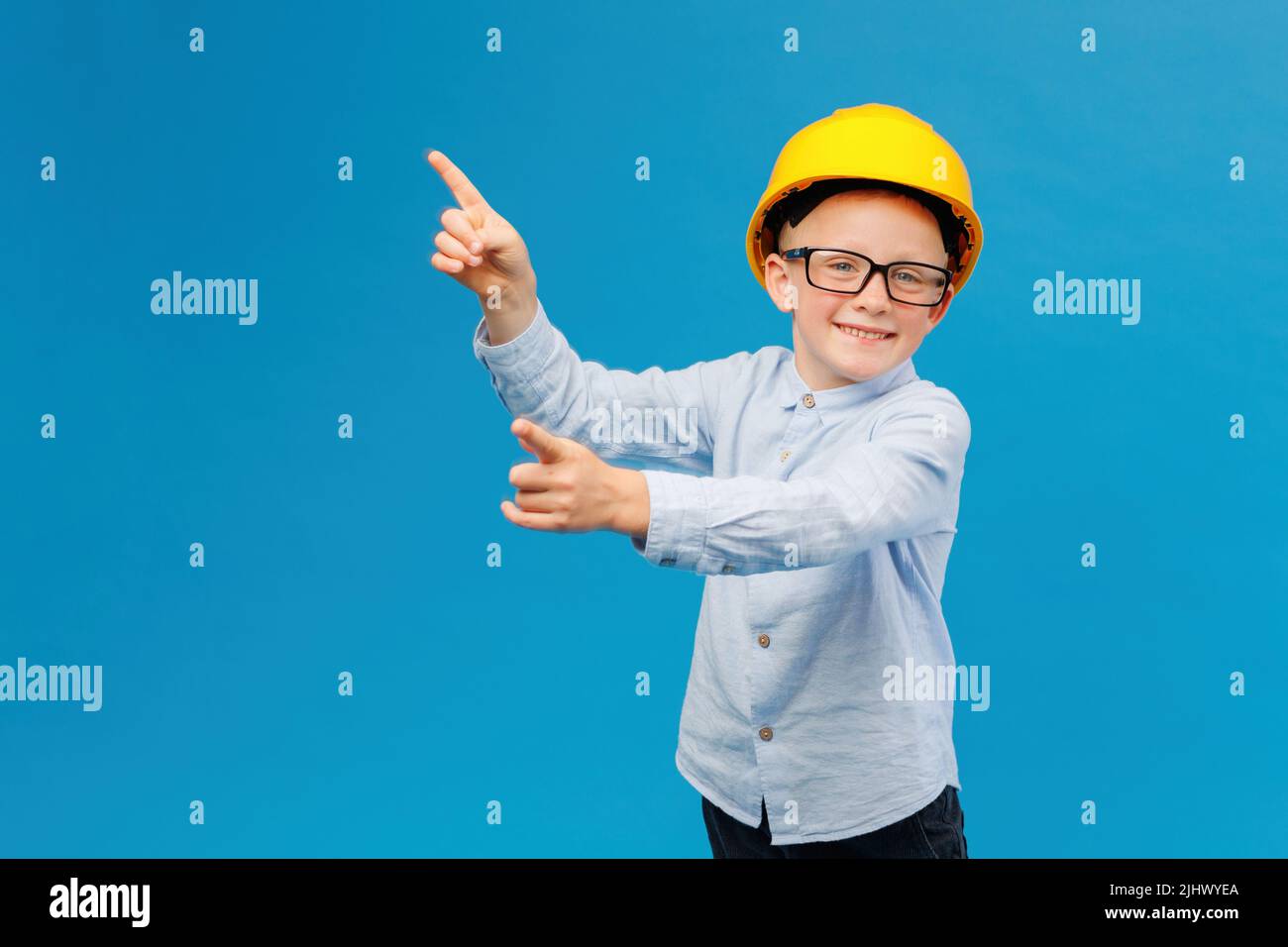 Cute boy construction worker in yellow hard hat standing in indoor