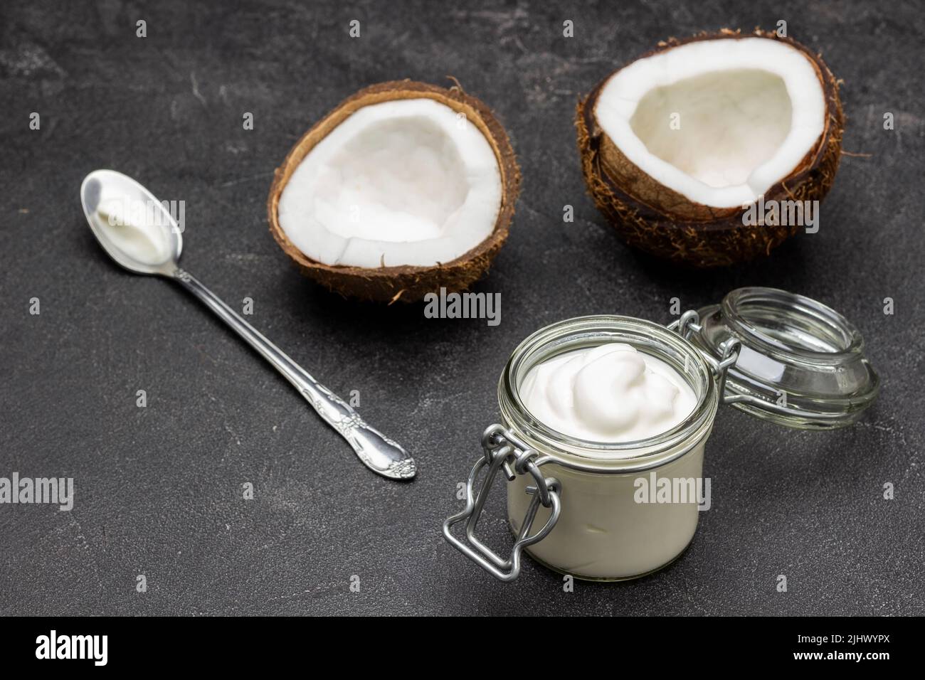 Two halves of coconut. Glass jar with coconut yogurt. Black background. Top view Stock Photo Alamy