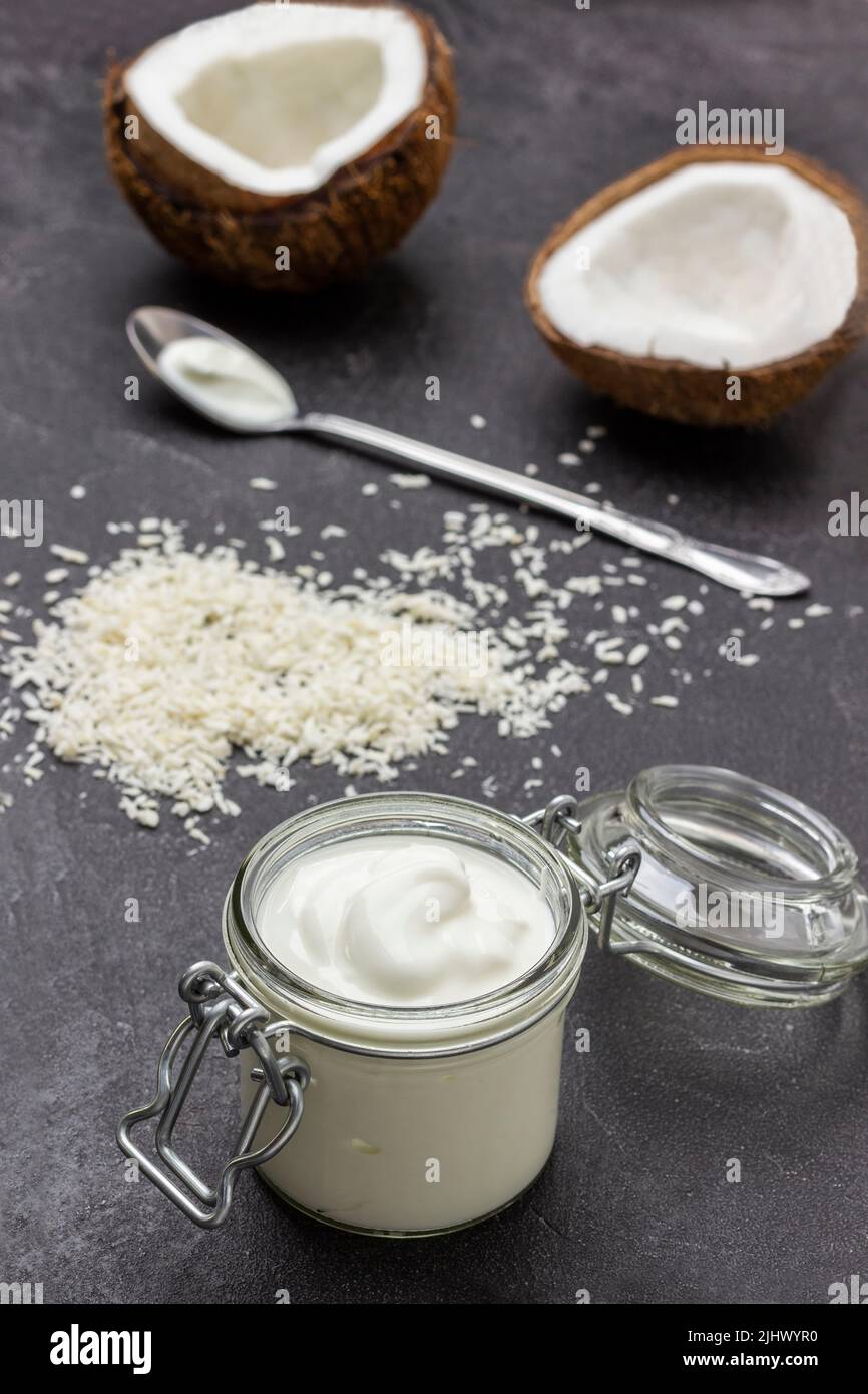 Glass jar with coconut yogurt. Two halves of coconut and coconut flakes