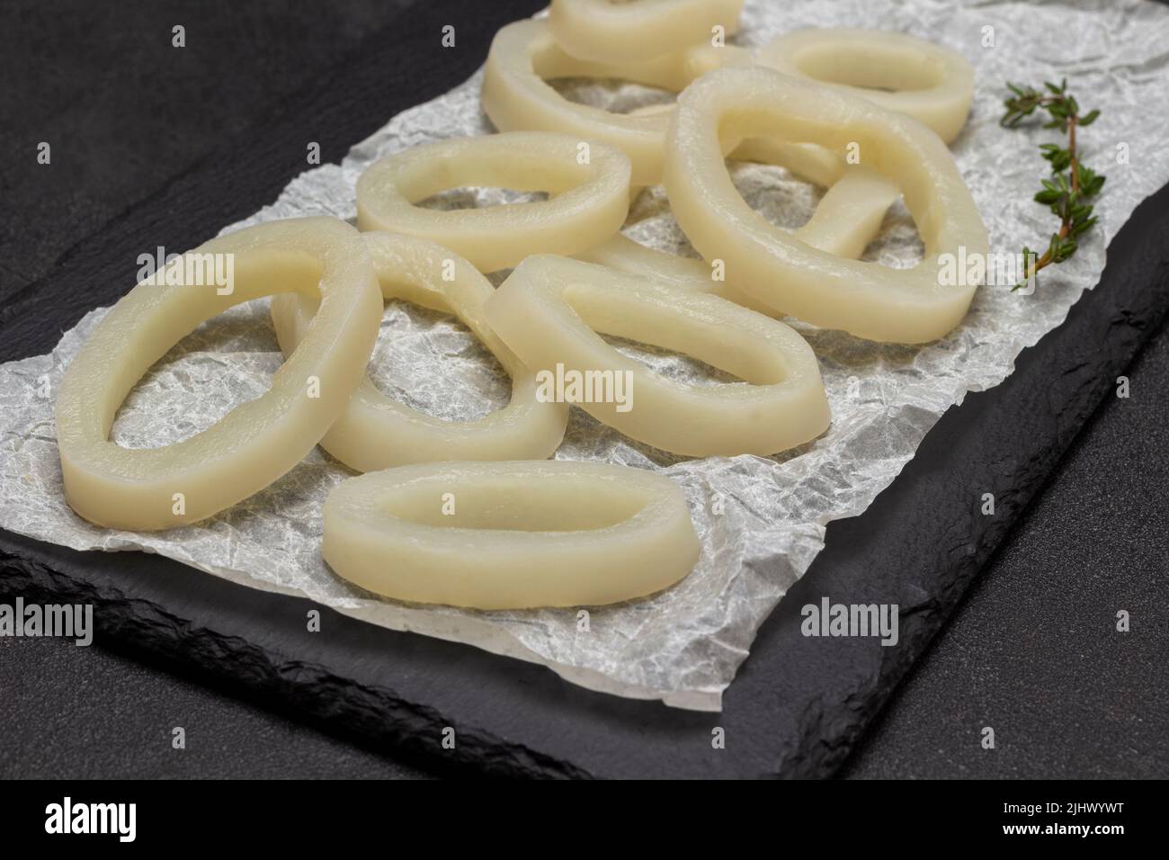Squid cut into rings on stone board. Top view. Black background Stock