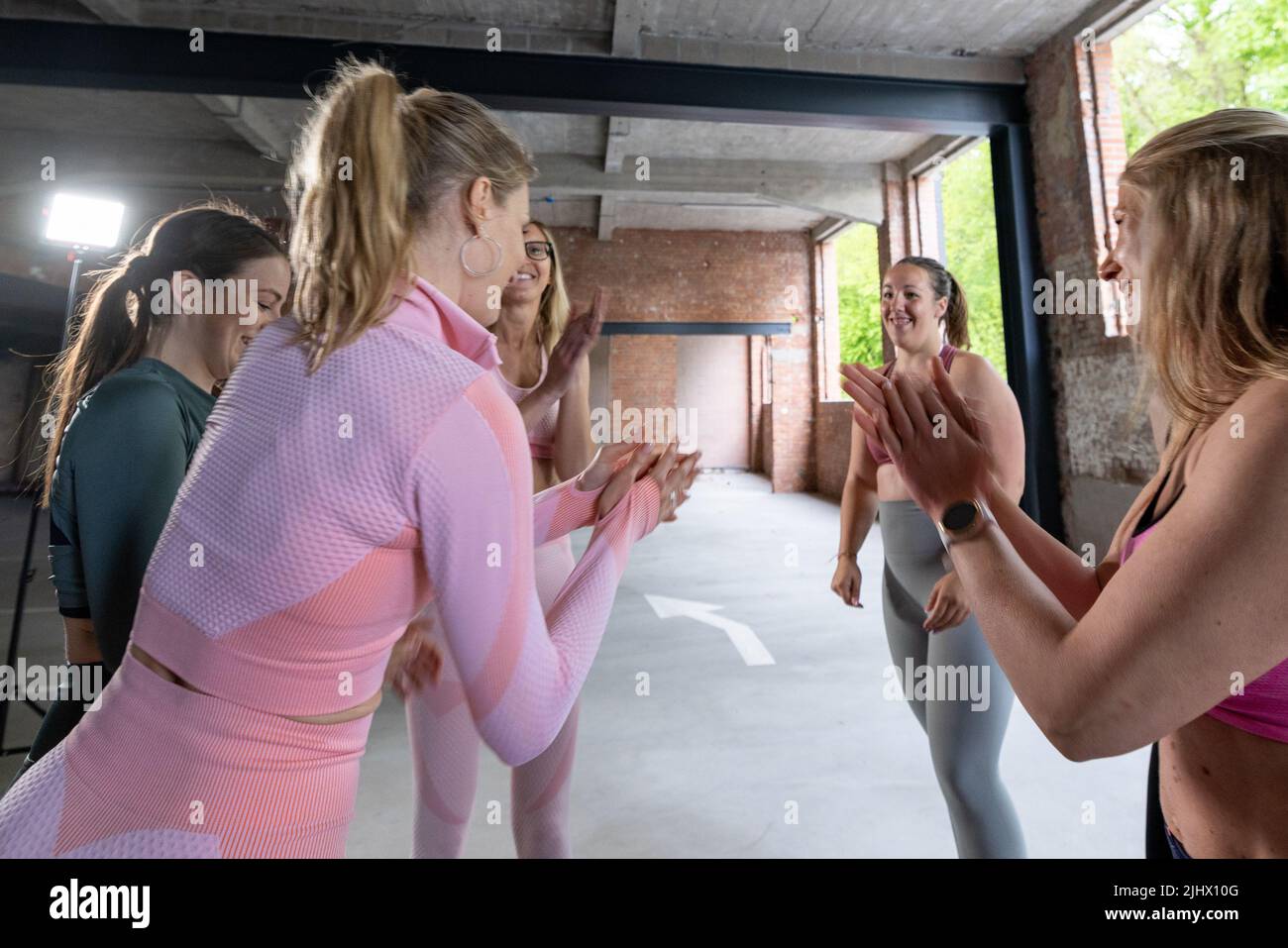 Group of six young motivated sporty girls wearing sports clothes standing together in a circle clapping their hands and cheering before or after a workout in fitness class. High quality photo Stock Photo