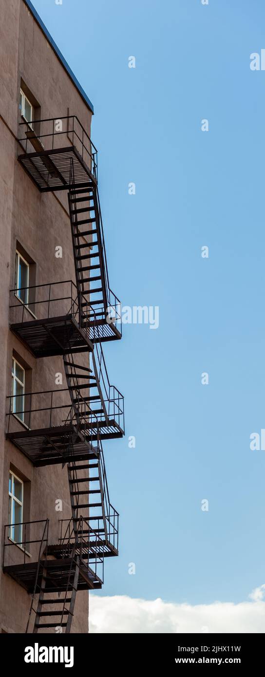 Silhouette of a fire escape on a high-rise building against a blue sky Stock Photo
