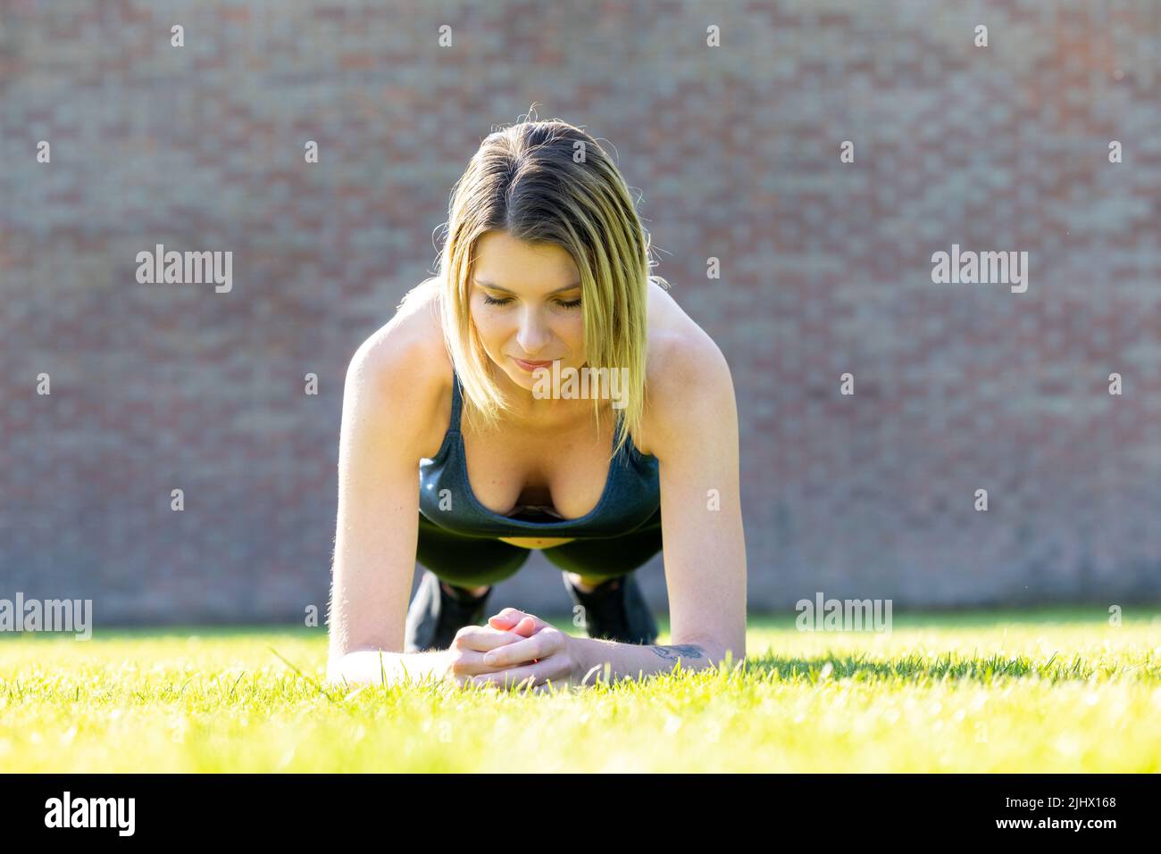 Attractive sporty woman concentrating in gym while doing fitness exercises. Young perfect shaped blonde doing plank. High quality photo Stock Photo