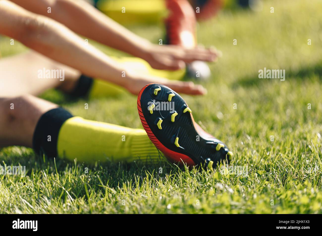 Football Player Stretches Sitting on Grass Pitch. Stretching Session