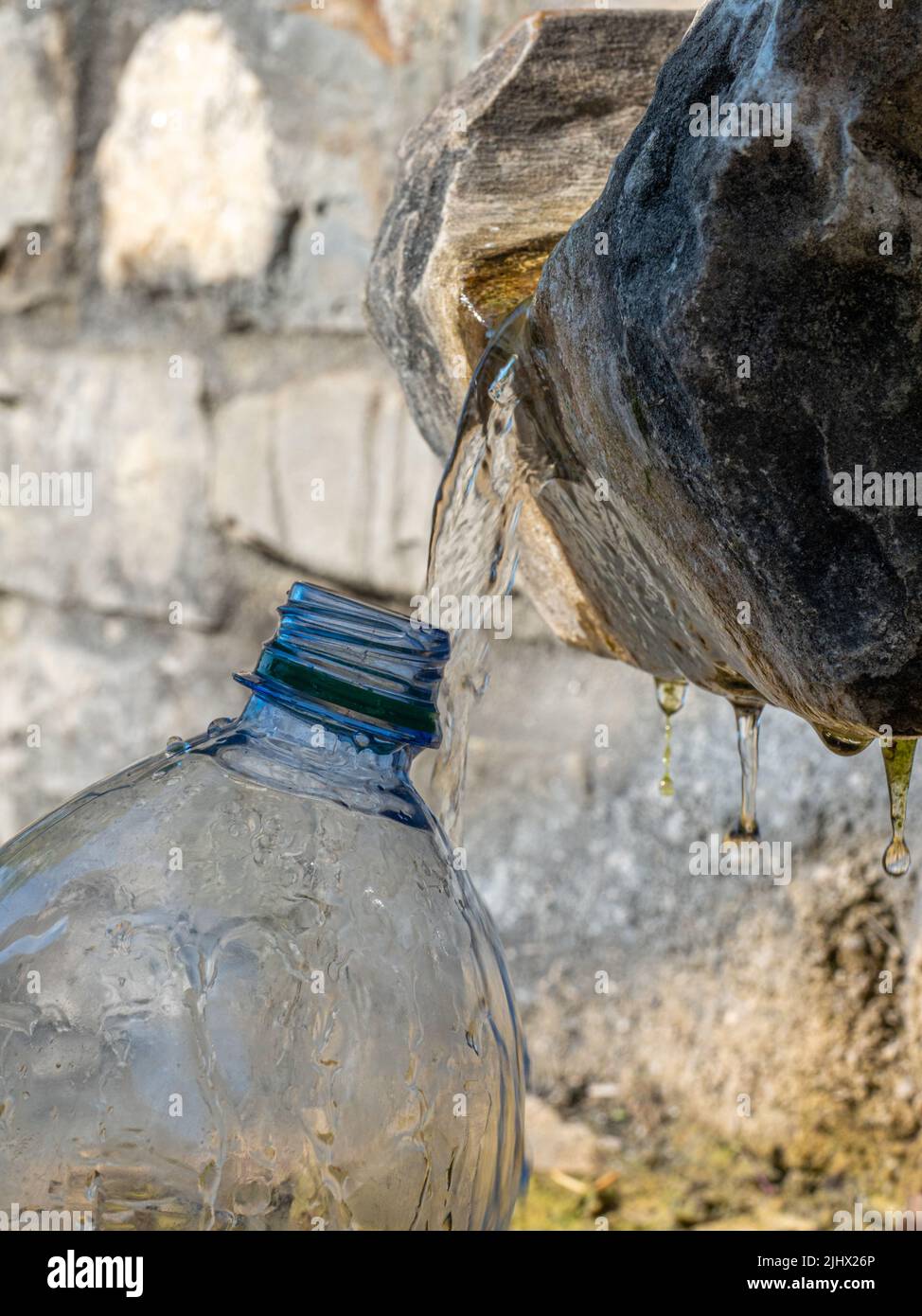 Drink spring water pouring in to bottle over sunlight and natural