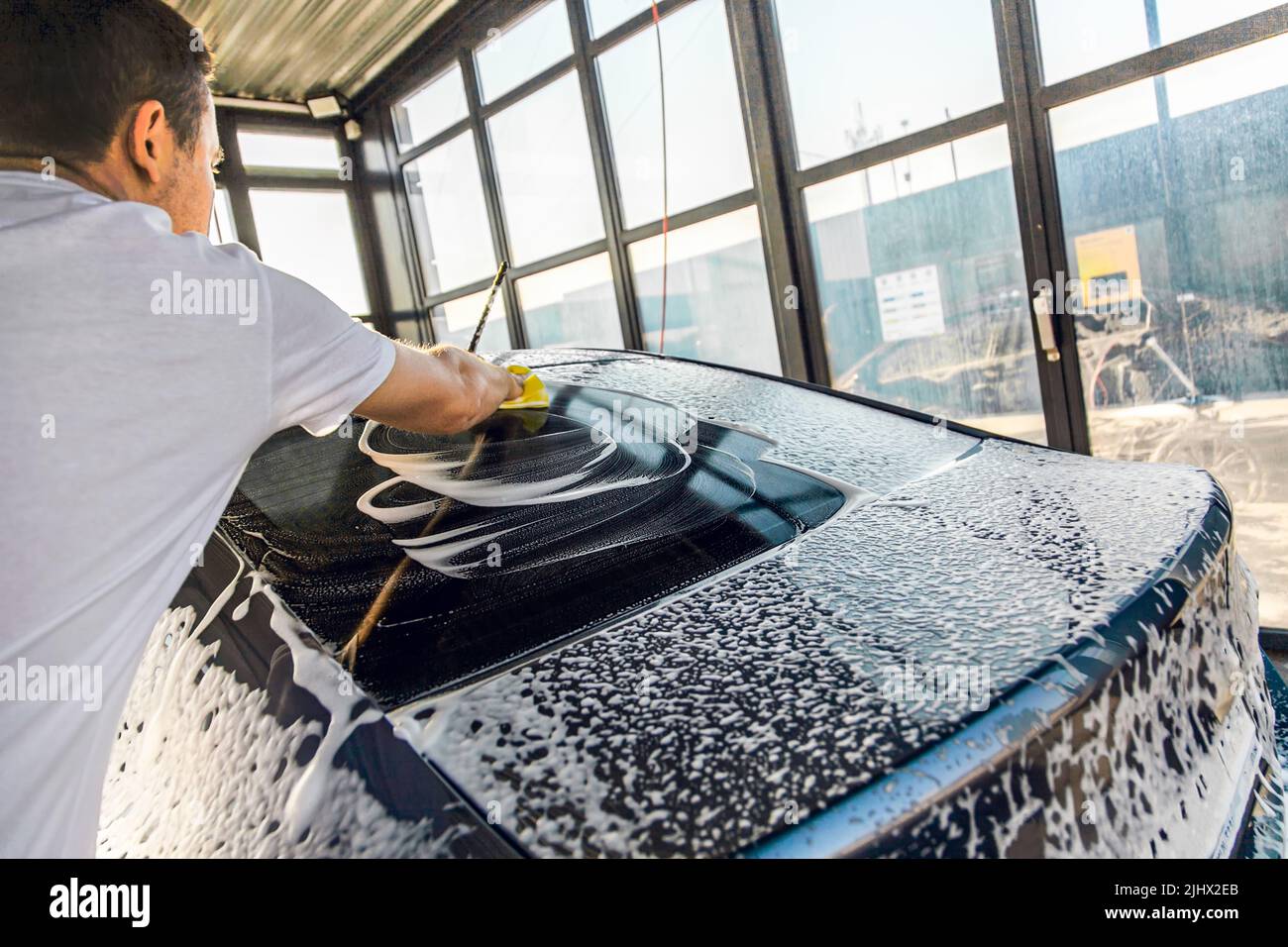 a-man-washes-his-car-with-foam-at-a-self-service-car-wash-stock-photo