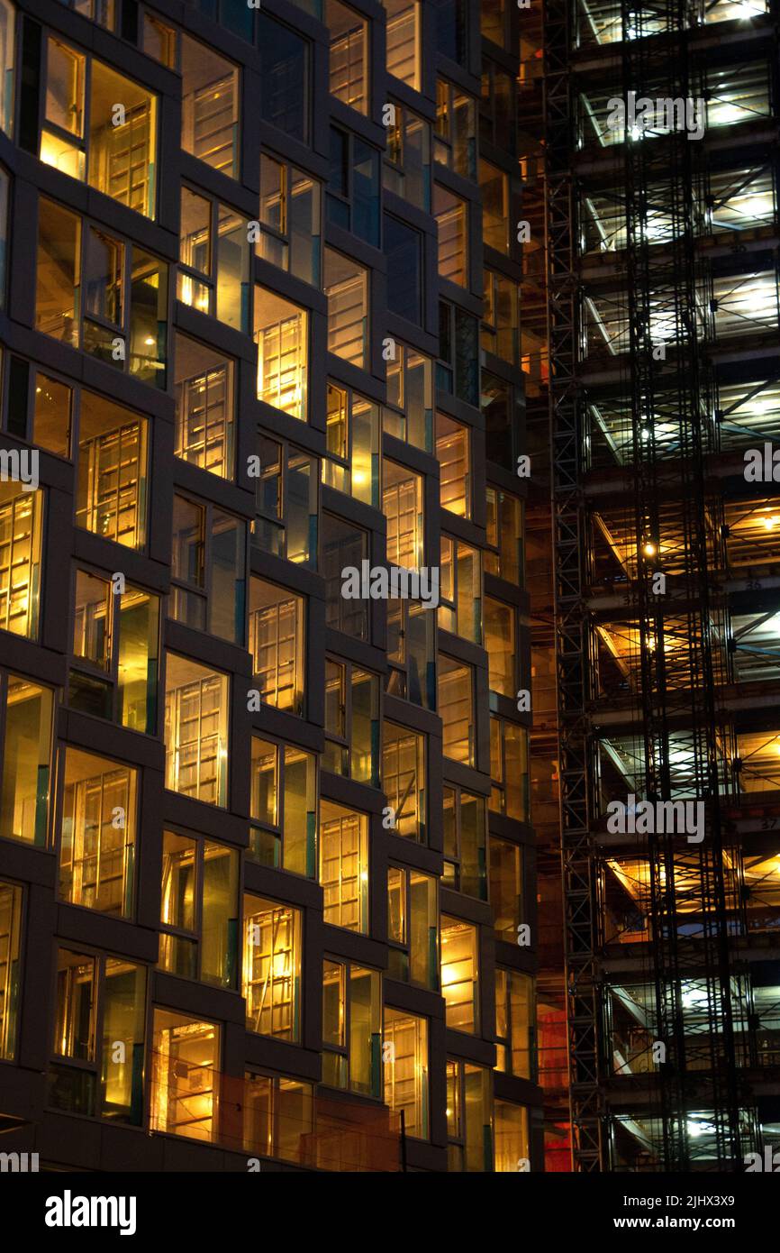 A vertical shot of an office building windows illuminated at night Stock Photo
