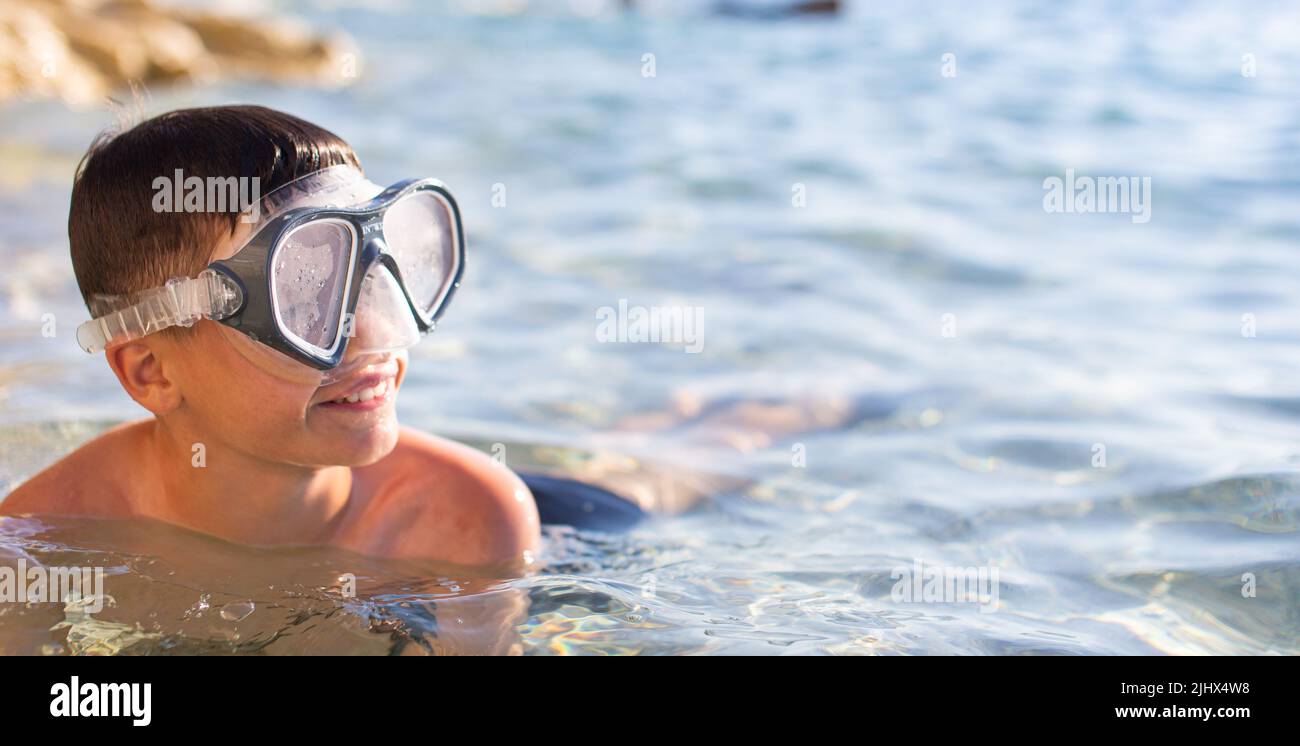 Happy Caucasian young boy with goggles in sea Stock Photo