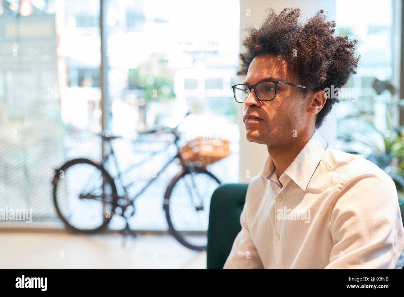 Thoughtful young start-up founder with afro hairstyle in his agency office Stock Photo