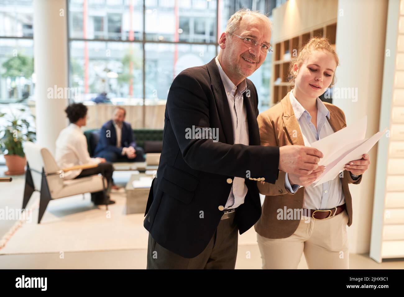 Senior businessman as trainer and young woman as trainee with business papers Stock Photo