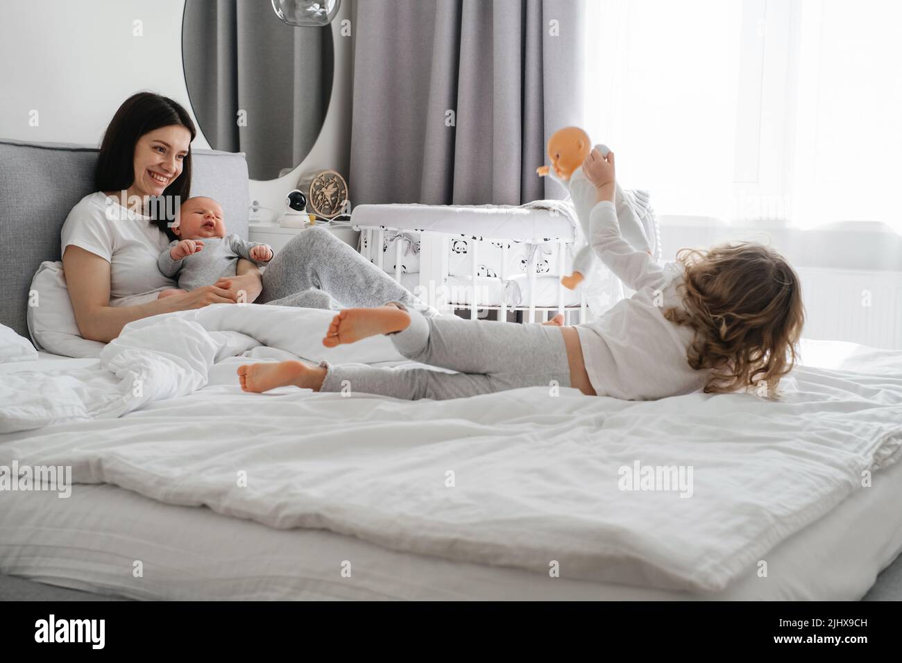 Mama with two kids at home in bedroom. Baby infant resting on mothers