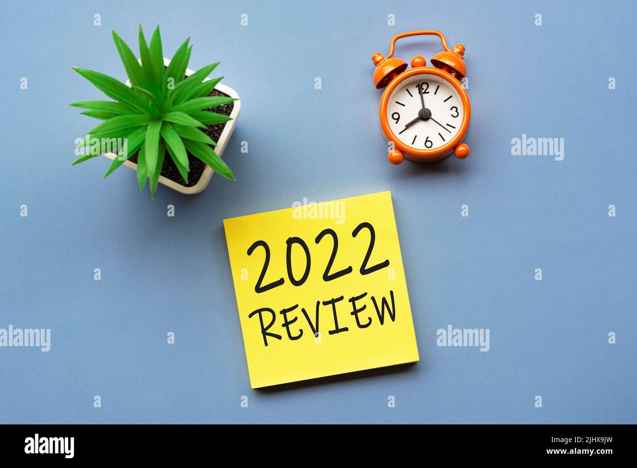 2022 Review written on Adhesive Note with alarm clock set at 8 o'clock. Stock Photo