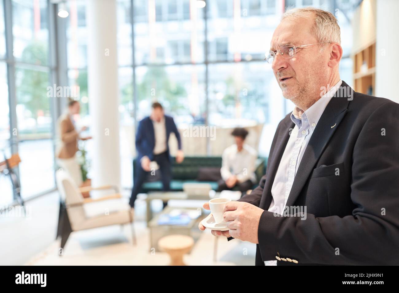 Thoughtful business man is standing with a cup of espresso on a break in the office Stock Photo