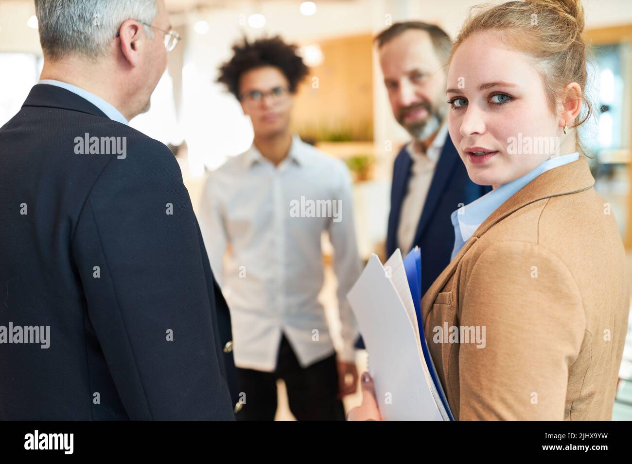 Young businesswoman with colleagues making small talk on the corridor in the office on a break Stock Photo