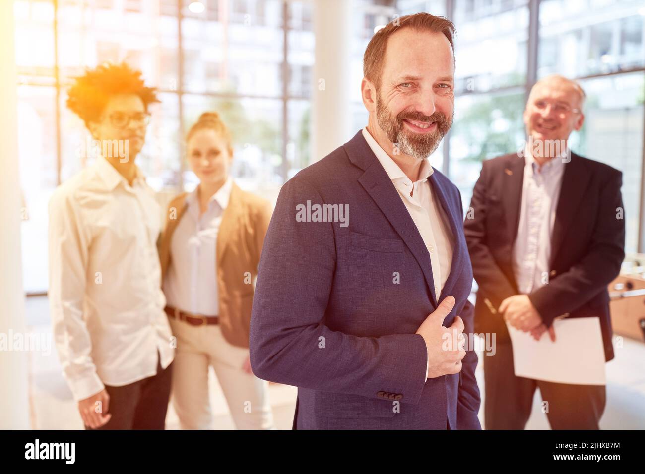 Successful businessman standing smiling in front of his business team ...
