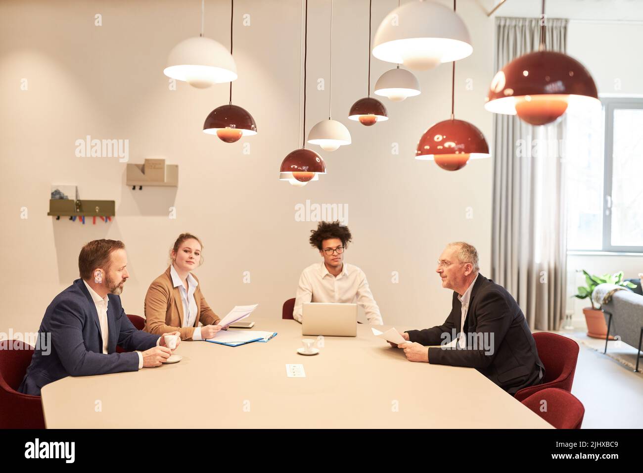 Group of business people sitting in a meeting at the table together in the conference room Stock Photo