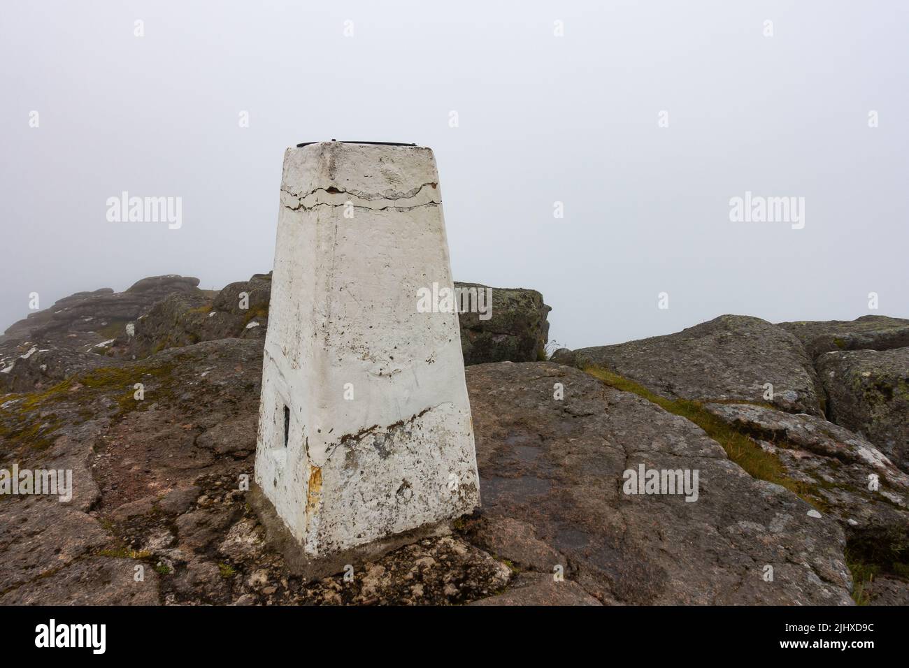 The white trig point at the summit of the corbett mountain of Ben Rinnes near Dufftown, Morayshire, Scotland on a foggy day Stock Photo
