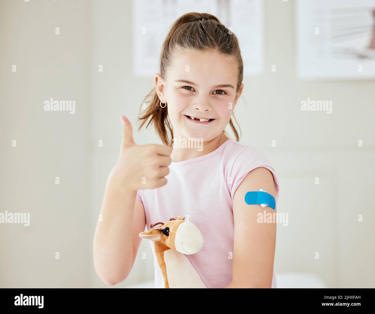 It went well. a little girl with a bandaid on her arm at a doctors office. Stock Photo