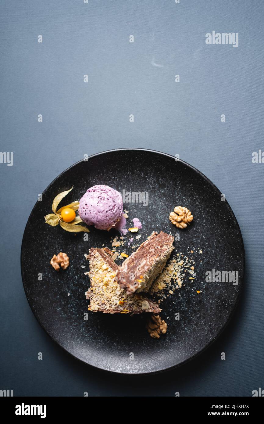 puff cake with chocolate custard, walnut and blueberry ice cream on black plate Stock Photo