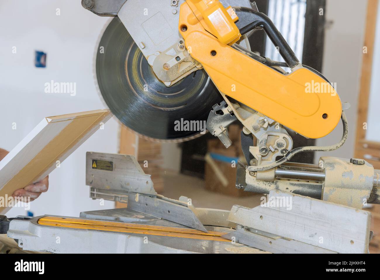 There is worker cutting wood moldings on circular saw to complete the