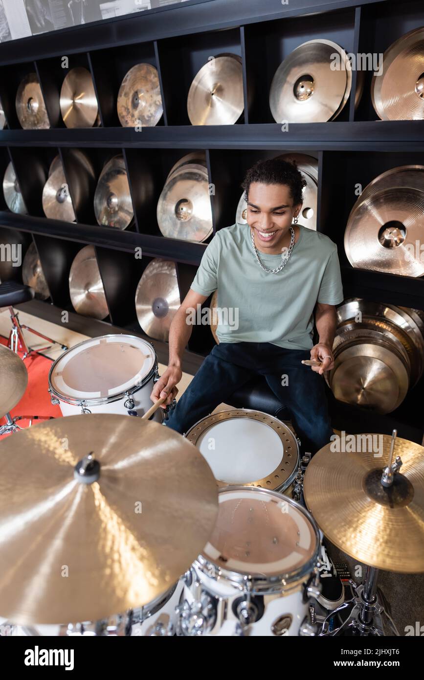 African american customer playing drums near plates in music store