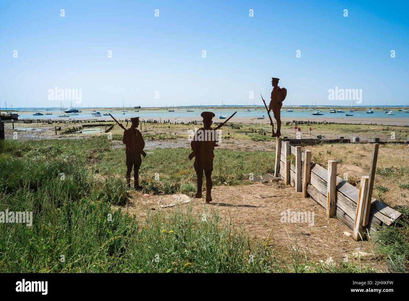 Remembrance, view of three commemorative  'Tommy' figures in silhouette sited on the beach in West Mersea, Mersea Island, Essex, England, UK Stock Photo