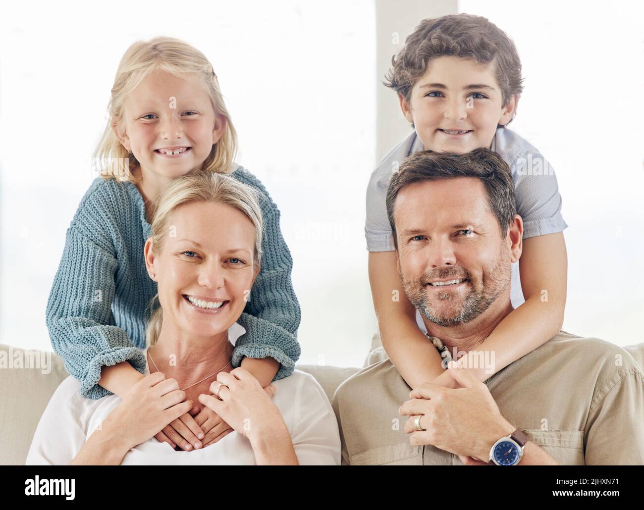 We have our hands full So are our hearts. a beautiful young family bonding on the sofa at home. Stock Photo