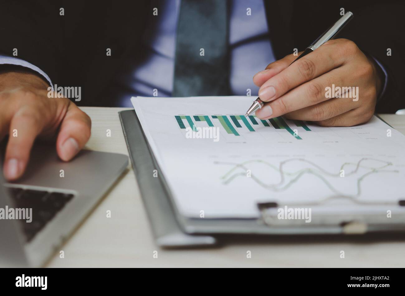 businessman holding pen to work computer graphs and charts data statistical data financial analysis documents. Stock Photo