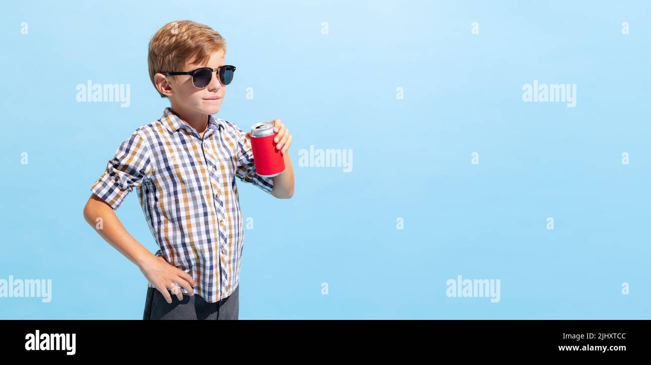 One cool little boy, kid in sunglasses posing isolated on light blue
