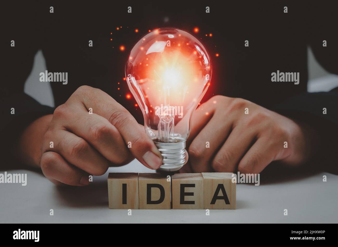 Text idea with a hand holding a light bulb Innovative wood cube block solution. Stock Photo