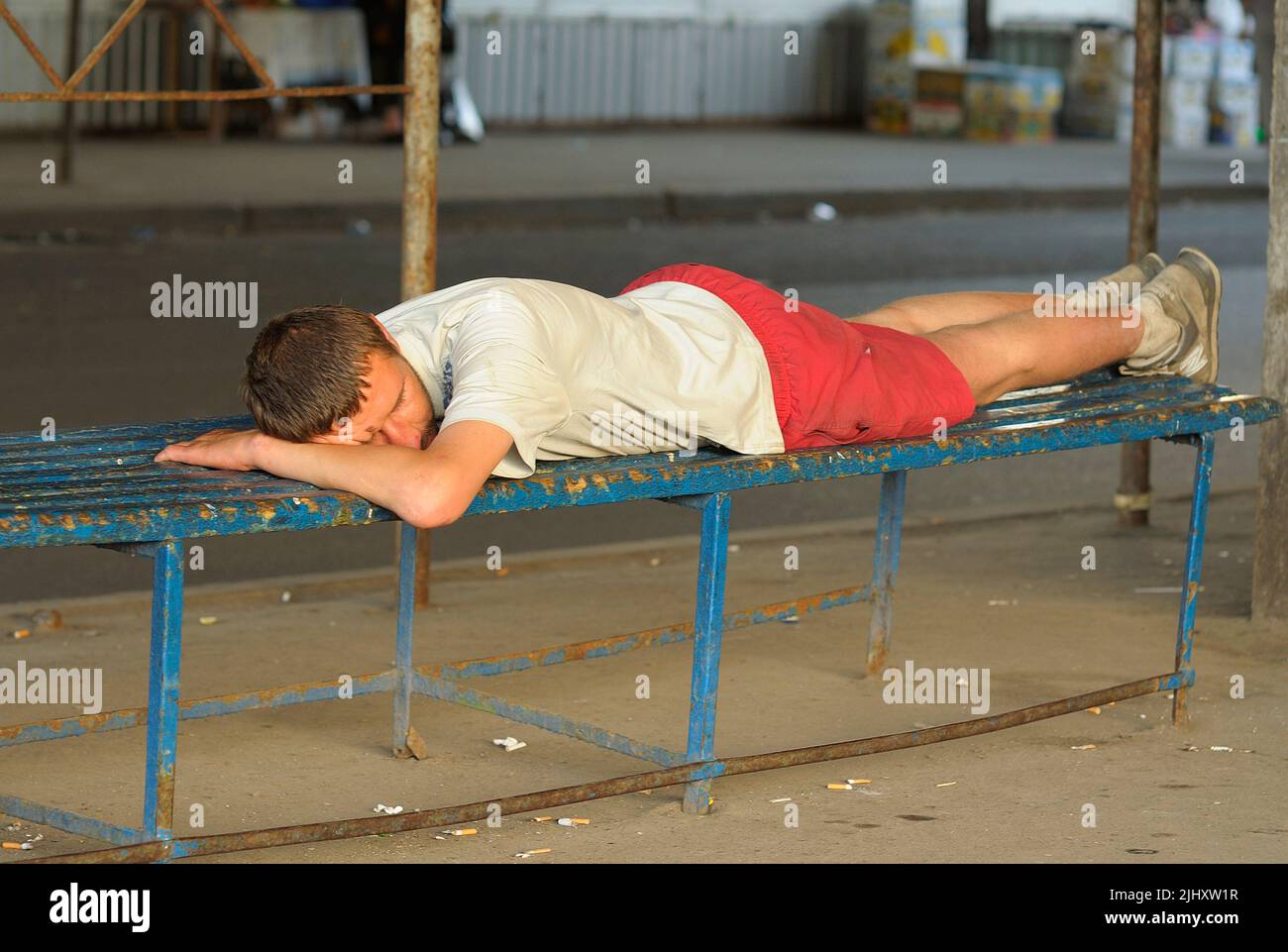 Man falling asleep on the bench of the bus stop in sweltering heat. July 25, 2012. Kiev, Ukraine Stock Photo