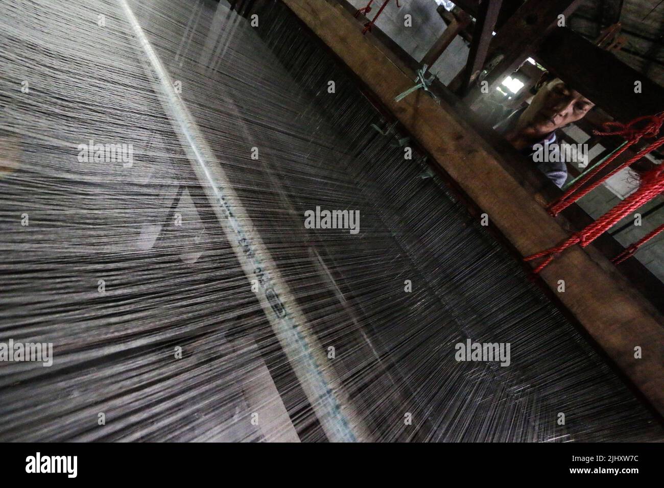 A worker works on a silk production line in Bogor, West Java, Indonesia on July 21, 2022. Stock Photo