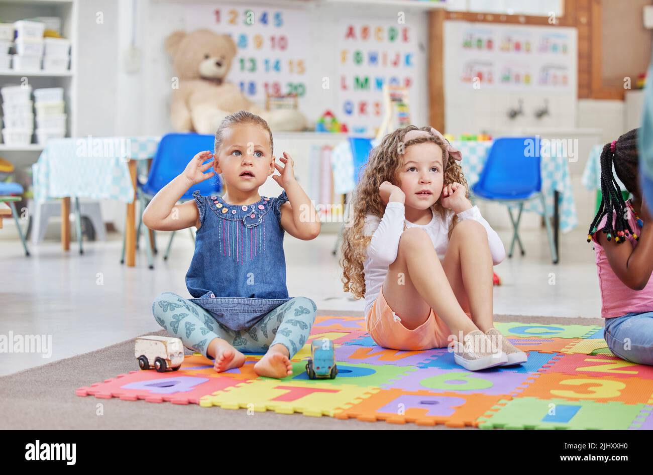 This song teaches us about all our body parts. two little girls sitting next to each other in class. Stock Photo